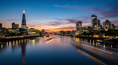 Long exposure twilight cityscape from bridge overlooking the shard and river with light trails and glass skyscrapers at sunset glow